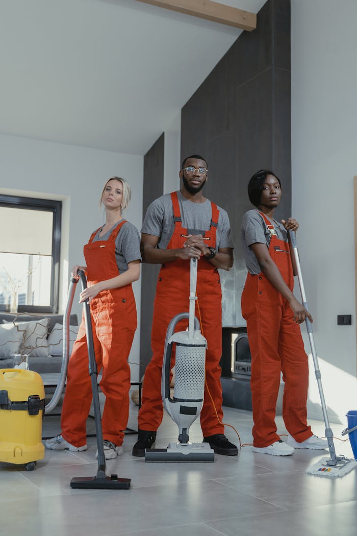 hero-img-01 Three cleaners in uniform with equipment in a modern home interior, showcasing teamwork and professionalism.